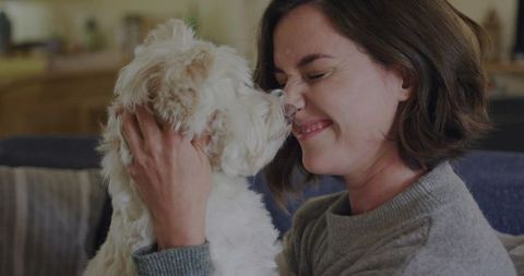 Happy woman enjoying cozy moment with adorable fluffy dog at home