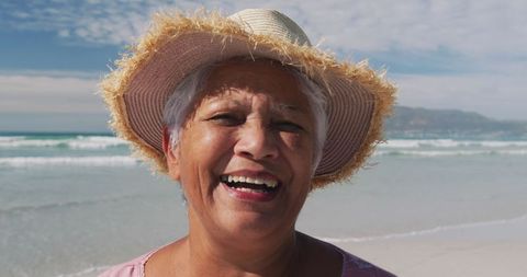 Joyful Senior Woman in Straw Hat Enjoying Sunny Beach Day
