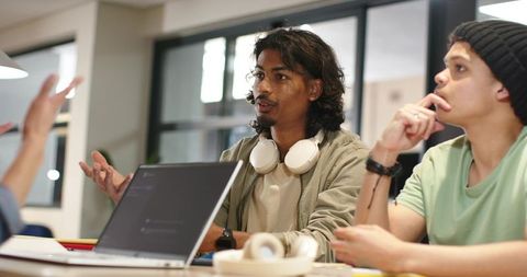 Multicultural students collaborating on college project in modern study space