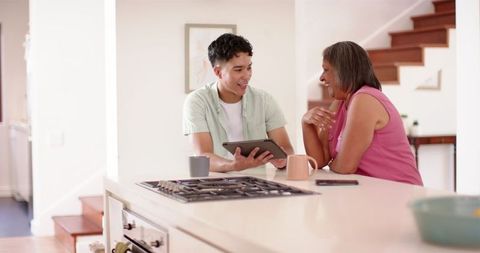 Physiotherapist Consults Senior Woman Using Tablet in Kitchen