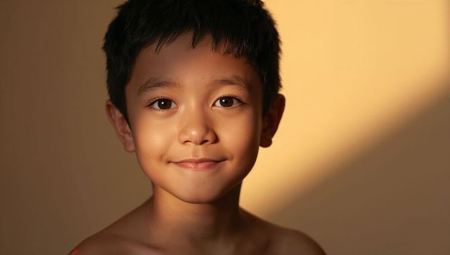 Smiling asian boy portrait with warm sunlit triangle and soft golden glow