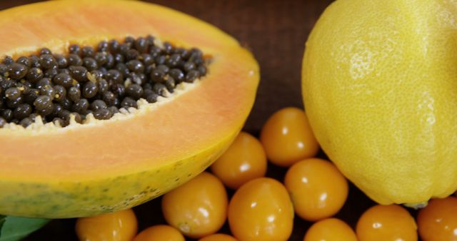 Bright, fresh tropical fruits including a sliced papaya with seeds, a whole lemon, and golden berries. Perfect for promoting healthy eating, fruit markets, tropical themes, and diet advertising. Vivid colors add visual appeal to designs and marketing materials centered on nutrition and wellness.