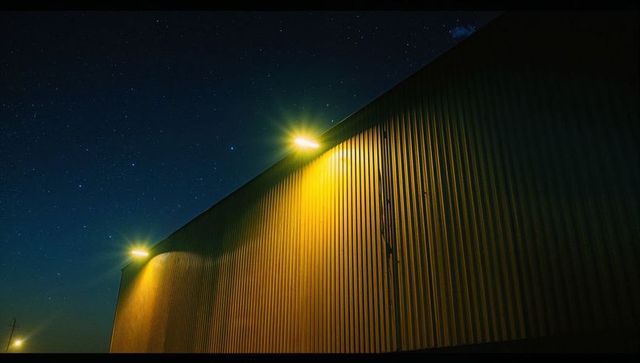Night Illumination on Industrial Warehouse Under Starry Sky