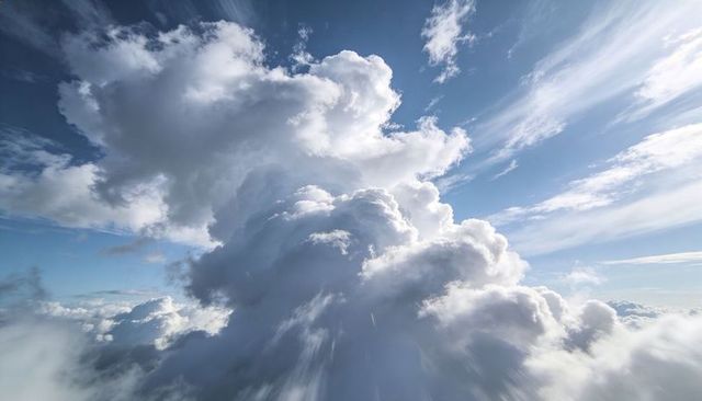 Towering Cumulus Clouds Rising Through Sunlit Sky with Cirrus Streaks and Dramatic Light