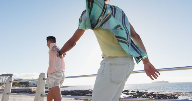 Couple holding hands walking along scenic coastal promenade - Download Free Stock Images Pikwizard.com