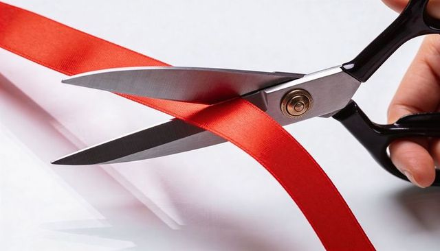 Precision scissors cutting red satin ribbon close-up for ceremony, packaging, gift wrapping