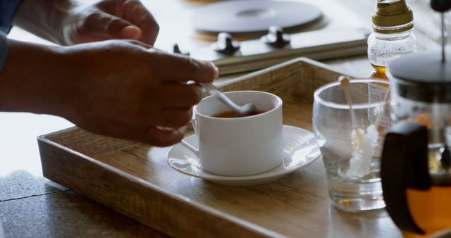 Person Stirring Tea in Cup on Wooden Tray in Rustic Kitchen - Download Free Stock Images Pikwizard.com