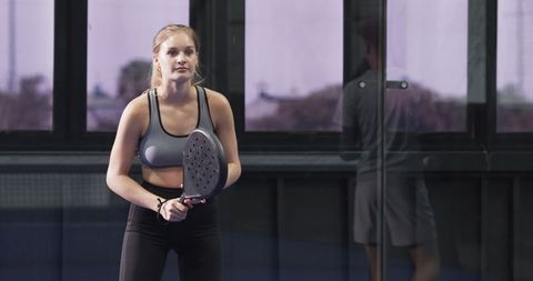 Female Padel Player Focused on Game in Modern Glass Court