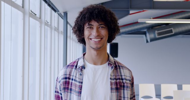 Smiling Young Man with Curly Hair in Modern Office Space - Download Free Stock Images Pikwizard.com