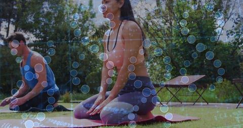 Woman meditating on yoga mat in backyard group fitness session with digital bubbles overlay