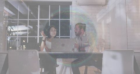 Colleagues collaborating over laptop in contemporary office meeting by window