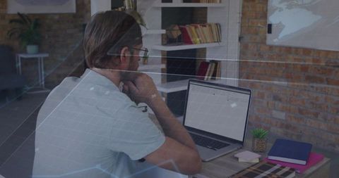 Remote professional leaning at desk checking laptop in brick home office with notebooks