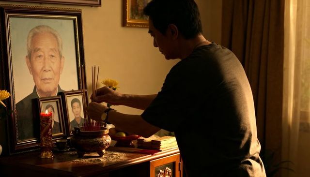 Honoring ancestor at home altar with incense, brass censer, candlelight and portrait