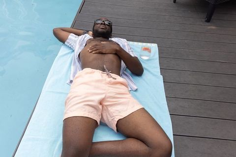 African american man relaxing on poolside towel in sunglasses enjoying summer leisure