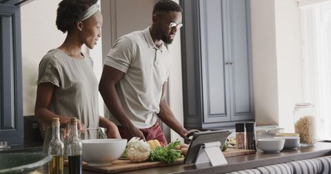Couple cooking in modern kitchen with tablet reference