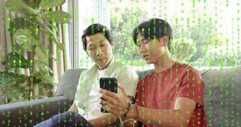 Teen presenting smartphone to father on sofa with matrix code overlay, digital learning