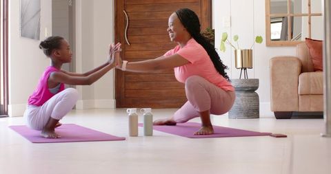 African american mom and daughter practicing yoga together at home for fitness and bonding