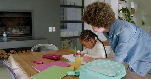 Mother helping daughter with homework in a cozy home environment