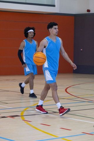 Athletic male basketball players dribbling on indoor court