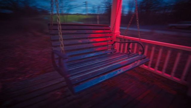 Empty Wooden Porch Swing at Dusk with Rustic Charm