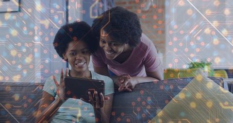 African american mother and daughter using tablet with digital circuit overlay at home