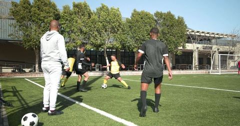 Soccer Coach Observing Team Training on Sunny Day