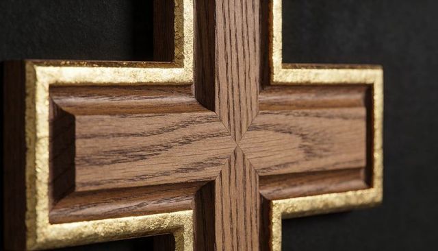 Carved oak cross featuring gilded edge detailing on dark textured backdrop