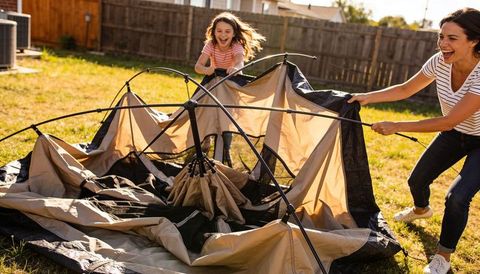 Mother and daughter assembling dome tent in sunny suburban backyard laughing together