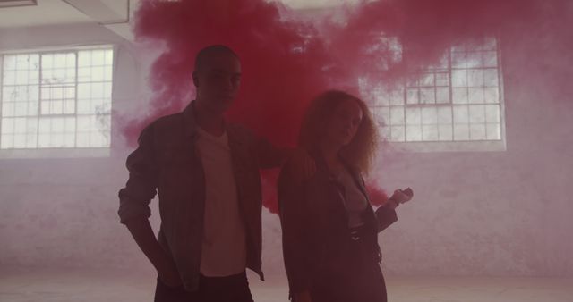 Biracial man and Caucasian woman stand confidently, with copy space. Their edgy style and the red smoke create a dramatic and artistic atmosphere.