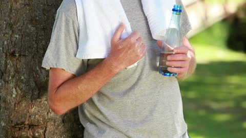 Mature Man Relaxing in Nature After Exercise with Water Bottle