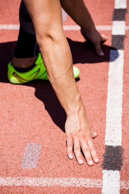 Close-up of an athlete's hand on the starting block, ready to sprint on a track. Ideal for use in sports-related content, fitness motivation, competition advertisements, and training guides.