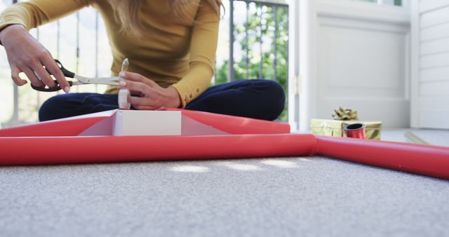 Woman Wrapping Holiday Gift Using Scissors and Red Wrap - Download Free Stock Images Pikwizard.com