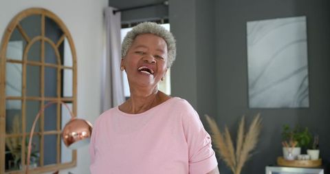 Joyful senior african american woman laughing in modern cozy living room portrait with natural light