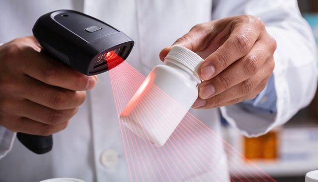 Pharmacist scanning medicine bottle with barcode scanner for pharmacy inventory tracking