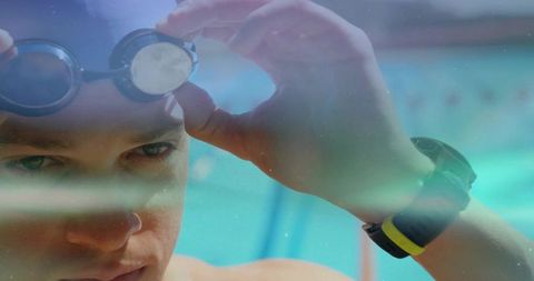Competitive swimmer adjusting mirrored goggles, close-up focused face with wrist tracker