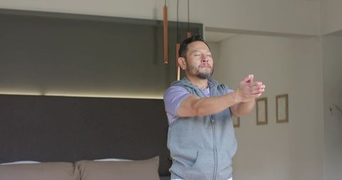 Middle-aged asian man stretching in minimalist bedroom