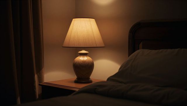 Warm amber bedside lamp casting cozy glow over wooden nightstand and bed