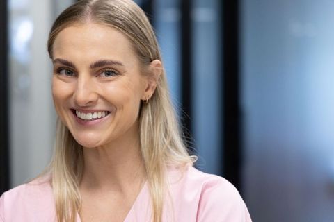Smiling professional woman wearing pink blouse close-up headshot for corporate branding
