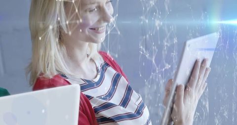 Smiling Woman Engages with Tablet and Digital Interface in Office