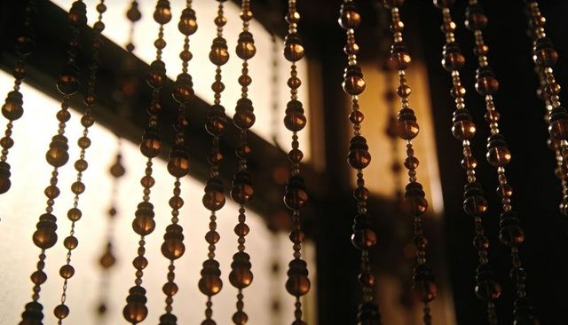 Amber bead curtain glowing with warm backlight through frosted window