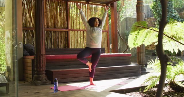 African american woman practicing yoga and meditating at vacation home. active and healthy lifestyle during vacation concept