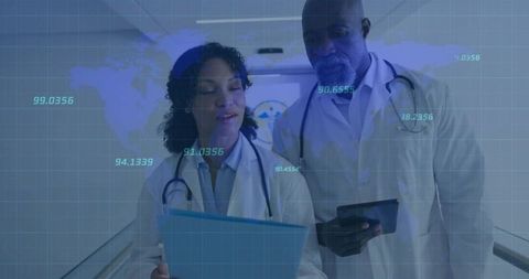 Doctors reviewing medical data on clipboard and tablet in corridor