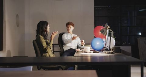 Colleagues brainstorming at night amid festive office decor