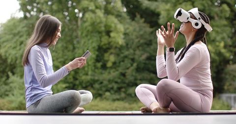 Friends using vr headset during outdoor yoga and fitness session in park