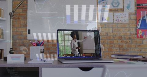 Remote teacher presenting lesson on laptop in modern home workspace with brick backdrop