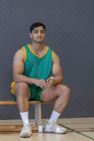 Male athlete relaxing on court wearing green yellow uniform
