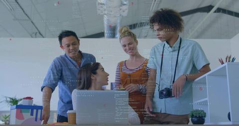 Creative team collaborating around laptop in modern open-plan studio with dslr camera