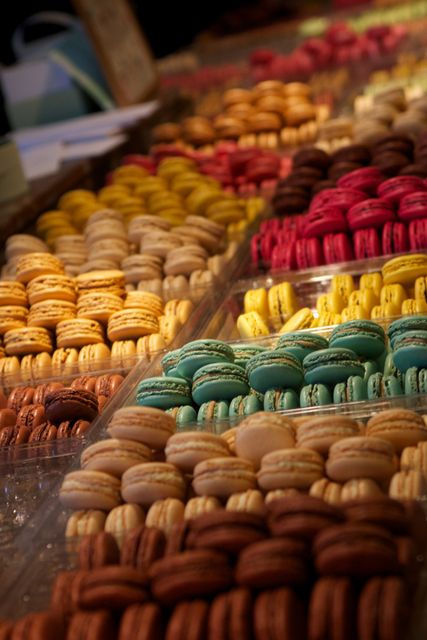 An array of colorful macarons on display. Useful for promoting bakeries, cafes, pastry shops, or websites focusing on desserts and gourmet treats. Perfect for marketing materials needing a vibrant, appetizing visual.