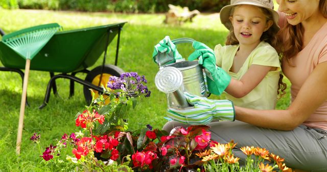 Mother and daughter enjoying a day in garden watering flowers, wearing gardening gloves and hats. This image can be used for lifestyle blogs, family-oriented content, gardening tips, outdoor activities, and promoting quality family time.