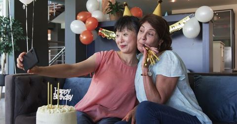 Senior friends taking selfies celebrating birthday party with cake